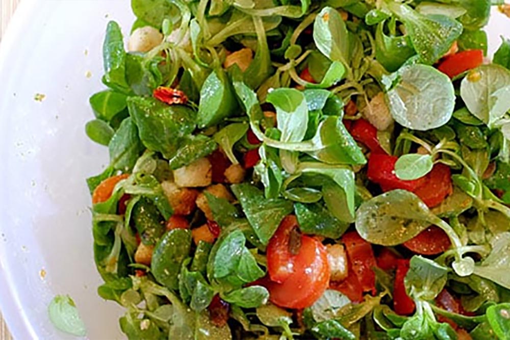 Salade van veldsla met tomaat, rode paprika en pestodressing